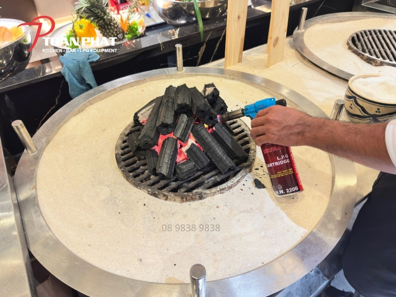 BẾP NƯỚNG CÁT DÙNG THAN 13 Làm nóng lớp cát của bếp nướng cát dùng than Toàn Phát trước khi nướng.